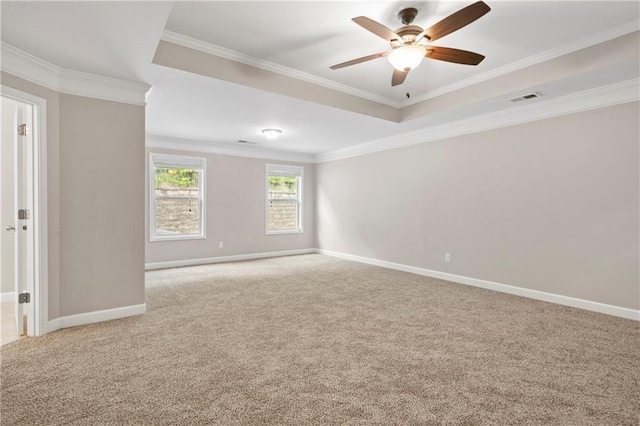 carpeted empty room featuring ceiling fan, ornamental molding, and a tray ceiling