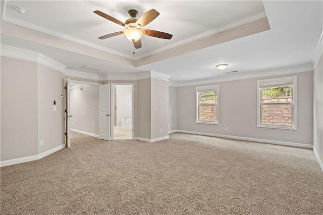 spare room with crown molding, light colored carpet, a tray ceiling, and ceiling fan