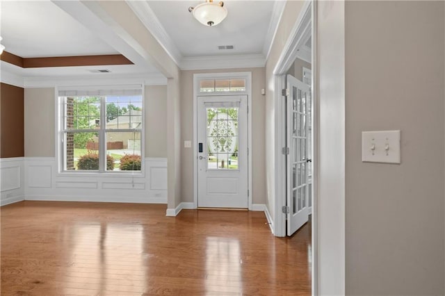 entrance foyer with wood-type flooring, a wealth of natural light, and crown molding