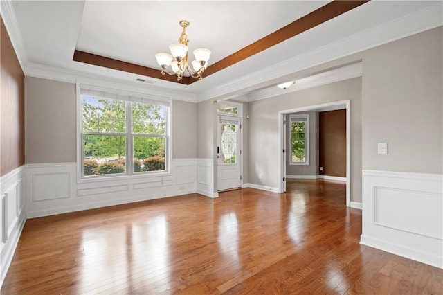 unfurnished room with wood-type flooring, a notable chandelier, crown molding, and a tray ceiling