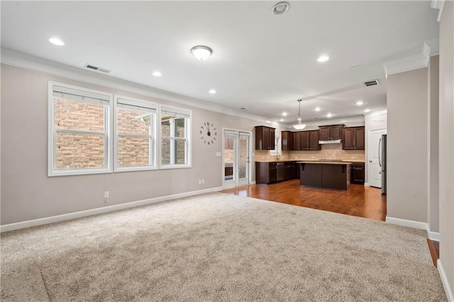 unfurnished living room featuring crown molding and dark carpet