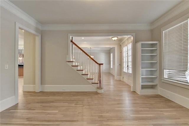 foyer with light wood-type flooring, crown molding, stairway, and baseboards