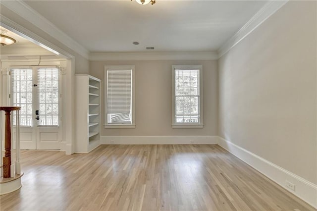 empty room featuring baseboards, crown molding, and wood finished floors