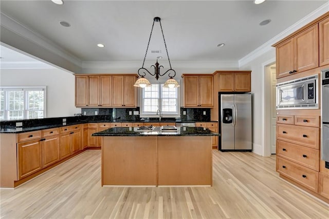 kitchen featuring stainless steel appliances, light wood-style flooring, decorative backsplash, ornamental molding, and a kitchen island