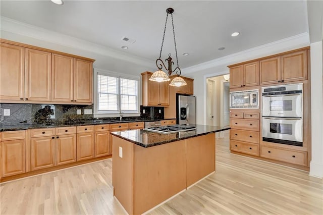 kitchen with appliances with stainless steel finishes, light wood-type flooring, a kitchen island, and a sink