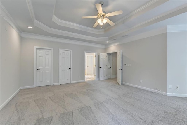 unfurnished bedroom with a raised ceiling, light colored carpet, and baseboards