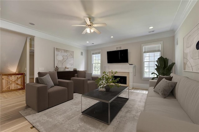 living room with light wood finished floors, ornamental molding, and a wealth of natural light