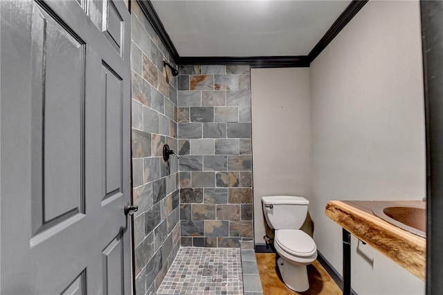 bathroom featuring tiled shower, crown molding, and toilet