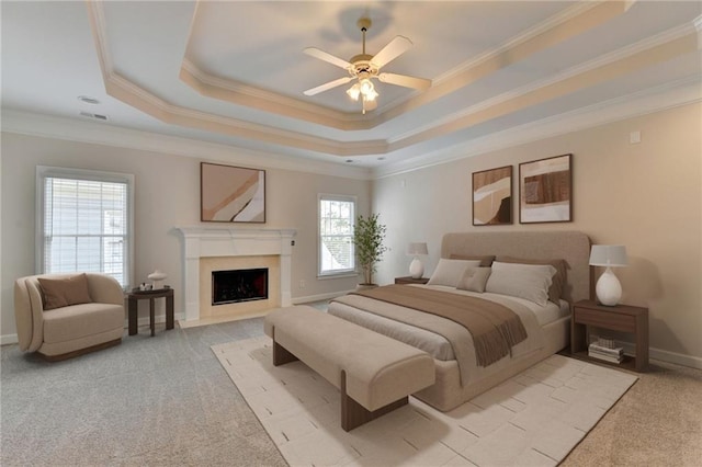 bedroom with light carpet, a high end fireplace, baseboards, a tray ceiling, and crown molding