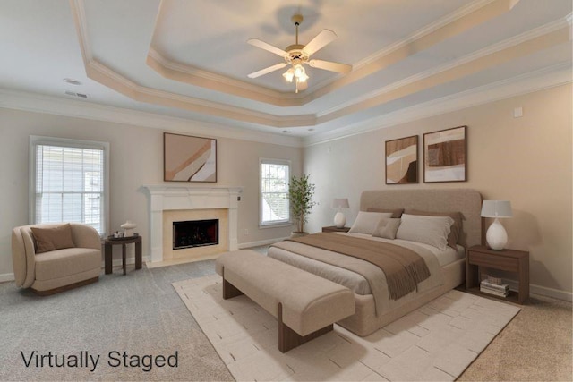 bedroom featuring a raised ceiling, light carpet, a fireplace, and baseboards