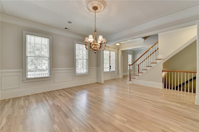 interior space featuring visible vents, stairway, wood finished floors, an inviting chandelier, and crown molding