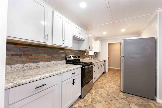 kitchen featuring appliances with stainless steel finishes, tasteful backsplash, stone finish flooring, and white cabinetry