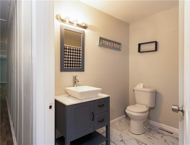 bathroom with vanity, toilet, marble finish floor, baseboards, and visible vents