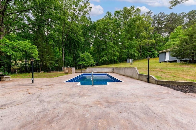 outdoor pool with a patio, an outbuilding, a lawn, and a storage shed