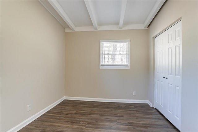 unfurnished bedroom with beamed ceiling, baseboards, dark wood-style flooring, and a closet