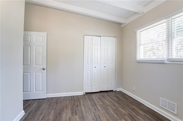 unfurnished bedroom with beamed ceiling, baseboards, visible vents, and a closet