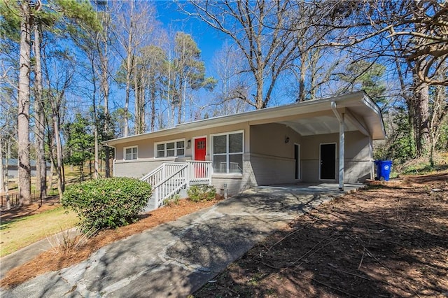 single story home featuring an attached carport, brick siding, concrete driveway, and stucco siding