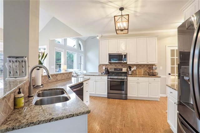 kitchen with decorative light fixtures, white cabinets, sink, and stainless steel appliances