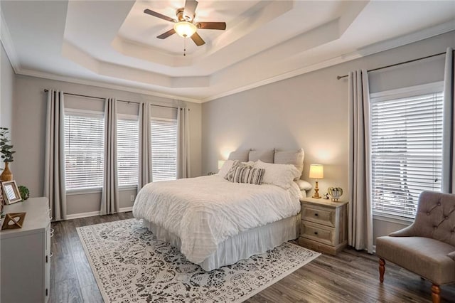 bedroom featuring ceiling fan, dark hardwood / wood-style flooring, a tray ceiling, and ornamental molding