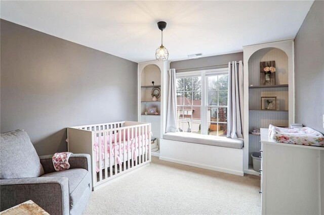 bedroom with light colored carpet and a nursery area