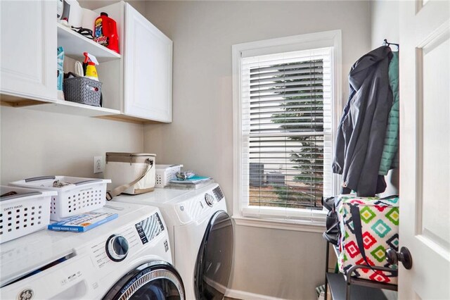 laundry area featuring washer and clothes dryer, a healthy amount of sunlight, and cabinets