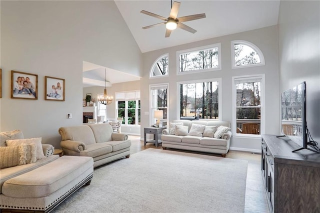 living room featuring high vaulted ceiling, light wood-type flooring, and ceiling fan with notable chandelier