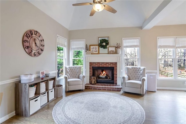 sitting room featuring ceiling fan, a brick fireplace, light hardwood / wood-style flooring, and lofted ceiling with beams