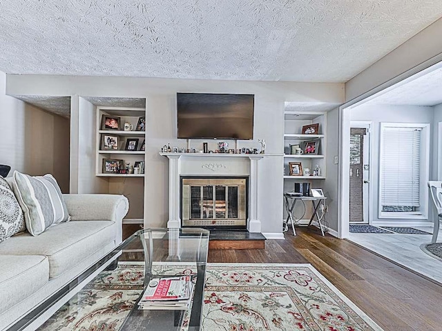 living room featuring a textured ceiling, built in features, and dark hardwood / wood-style floors