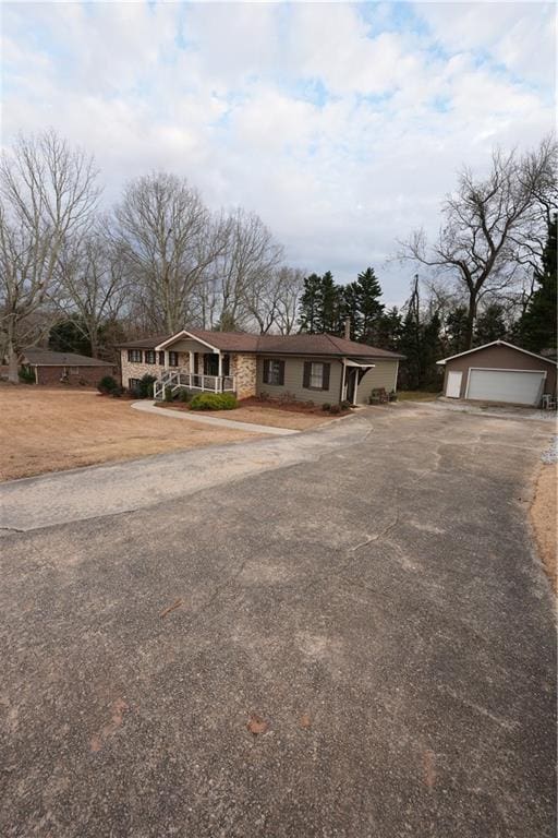 single story home with a garage, a porch, and an outbuilding