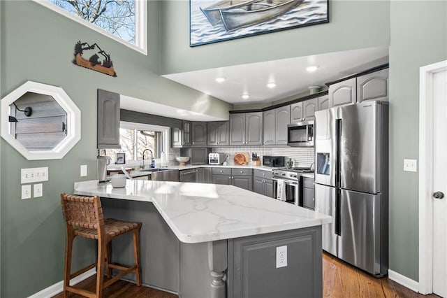 kitchen featuring gray cabinets, tasteful backsplash, hardwood / wood-style flooring, stainless steel appliances, and sink