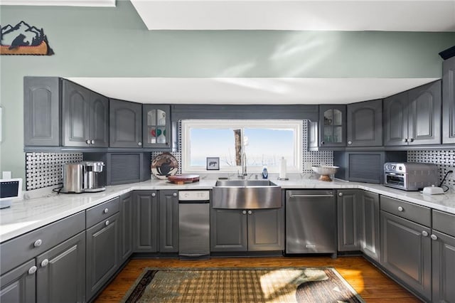 kitchen with decorative backsplash, dishwasher, wood-type flooring, and gray cabinetry