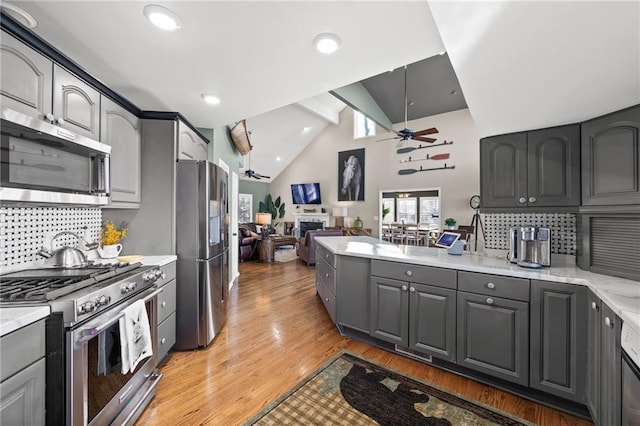 kitchen featuring appliances with stainless steel finishes, light hardwood / wood-style flooring, ceiling fan, and backsplash