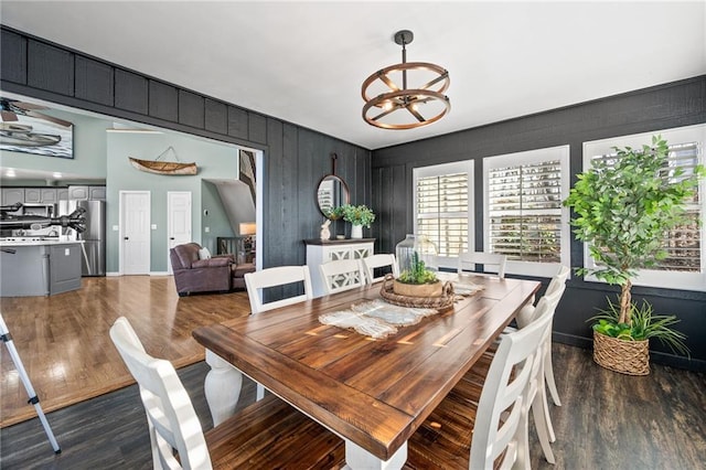 dining space with wood walls, hardwood / wood-style floors, and a chandelier