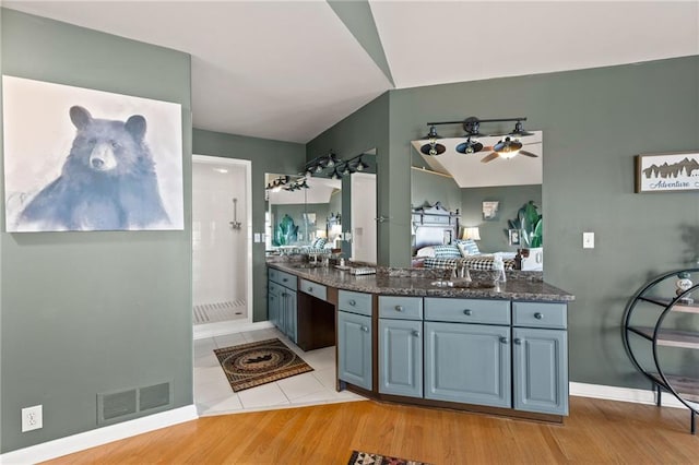 interior space featuring baseboards, visible vents, vaulted ceiling, walk in shower, and vanity