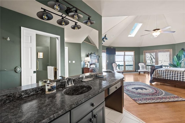 bathroom featuring vanity, ceiling fan, high vaulted ceiling, a skylight, and tile patterned flooring