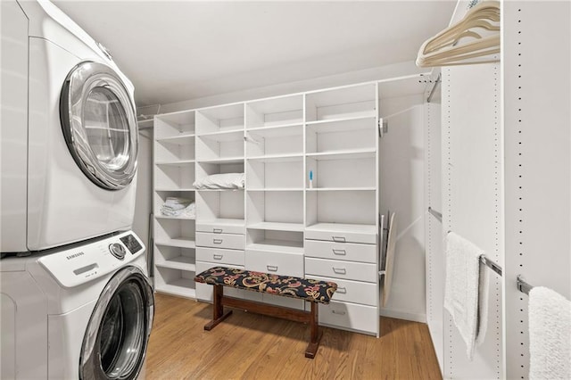 laundry area featuring stacked washer and clothes dryer and light hardwood / wood-style flooring