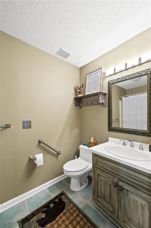 bathroom with tile patterned flooring, toilet, vanity, and a textured ceiling