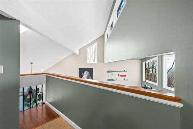 hallway featuring a healthy amount of sunlight, lofted ceiling with beams, baseboards, and wood finished floors