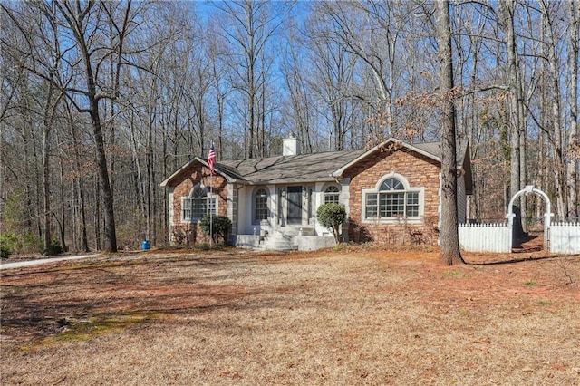 ranch-style house with brick siding, fence, and a chimney