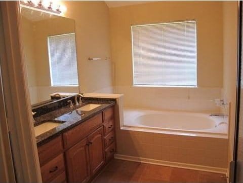 bathroom with tiled tub and vanity