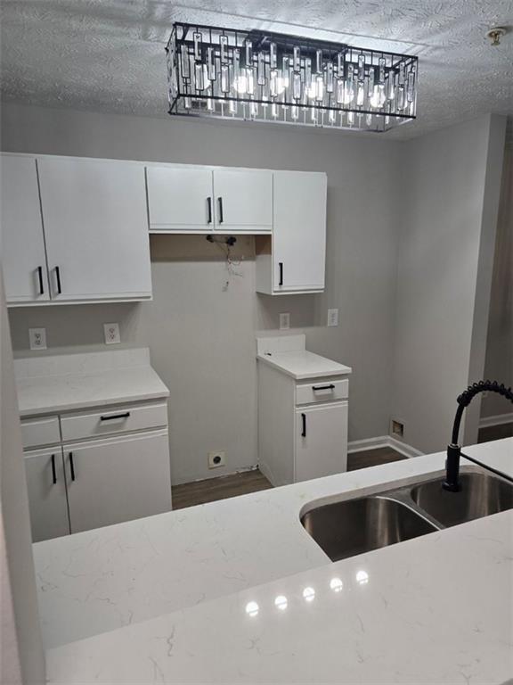3201 Fairington Dr, Lithonia, GA 30038 - kitchen with a sink, white cabinets, light stone countertops, and a textured ceiling
