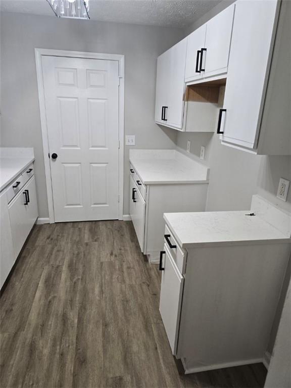 3201 Fairington Dr, Lithonia, GA 30038 - kitchen with dark wood-style floors, white cabinetry, light countertops, a textured ceiling, and baseboards