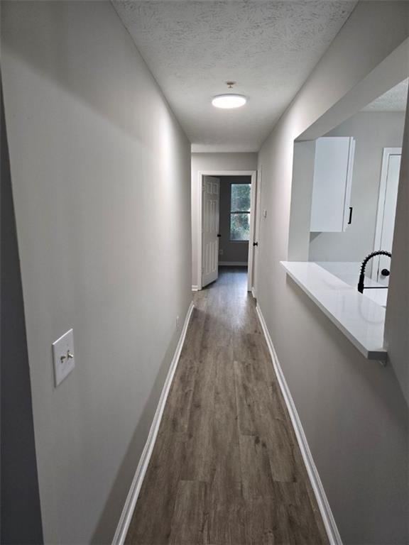 3201 Fairington Dr, Lithonia, GA 30038 - corridor with dark wood-type flooring, a textured ceiling, baseboards, and a sink