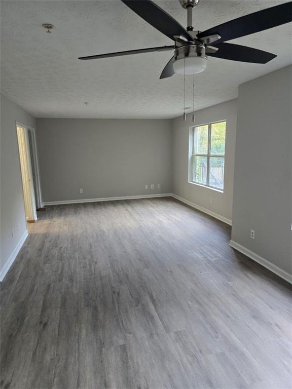 3201 Fairington Dr, Lithonia, GA 30038 - empty room with a textured ceiling, dark wood-style floors, ceiling fan, baseboards, and fire sprinkler in ceiling