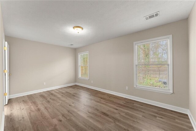 unfurnished bedroom with visible vents, baseboards, and wood finished floors