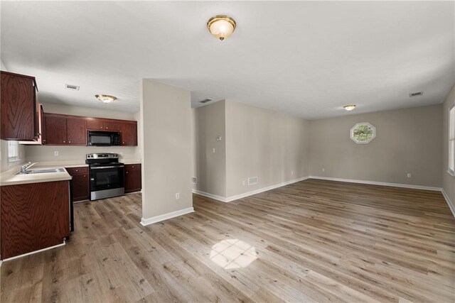 kitchen featuring visible vents, light wood-style flooring, light countertops, black appliances, and a sink