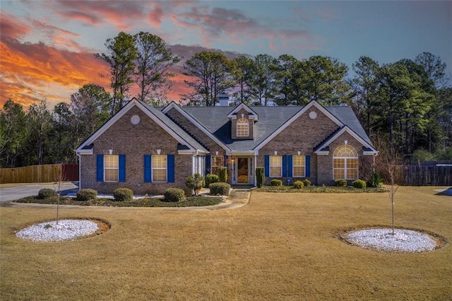 view of front facade with a front lawn, fence, and brick siding