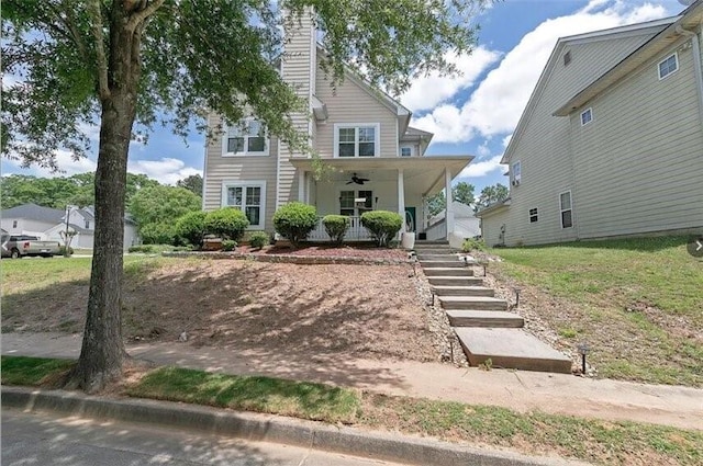 view of front of home featuring a chimney, covered porch, ceiling fan, and stairs