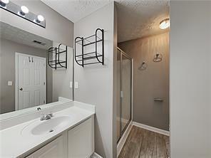 full bath featuring a textured ceiling, vanity, wood finished floors, a stall shower, and baseboards