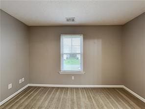 spare room featuring wood finished floors, baseboards, and visible vents